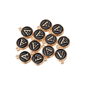 Macro detail of round black enamel letter A charms with gold plating for DIY jewelry making