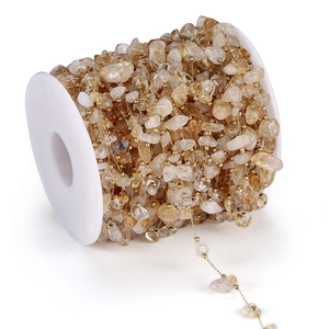 Dettaglio di perle in pietra naturale gialla e perle dorate su bobina per gioielli
