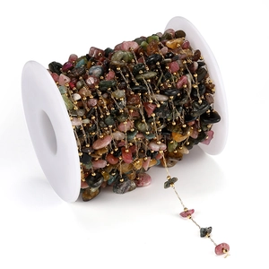 Dettaglio macro di catena in pietre naturali multicolore avvolta su rocchetto di plastica