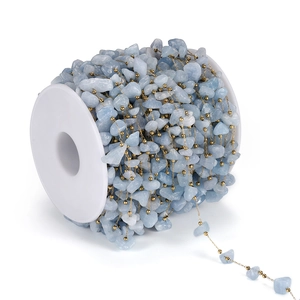 Dettaglio di perline in pietra naturale azzurra con catena dorata su rocchetto di plastica