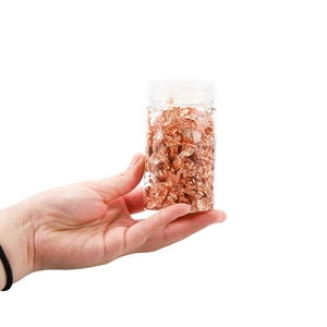 Jar of metallic rose gold leaf flakes for nail art and craft decoration on white background