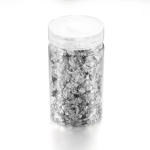 Macro view of bright silver foil flakes in a clear jar for nail art and DIY decor