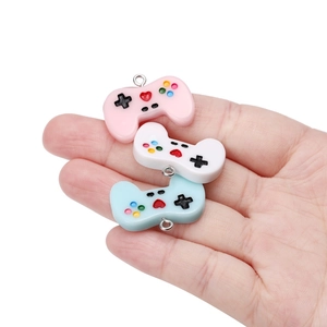 DIY resin game controller charms for necklaces shown in hand for size comparison