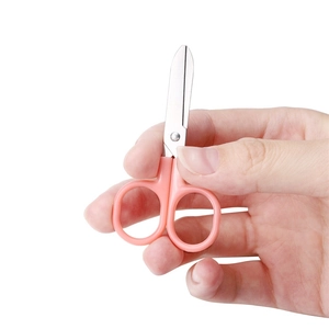 Macro view of compact safety scissors with pink handles being held to show small size