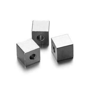 Macro shot of three stainless steel cube beads with precise holes for DIY jewelry