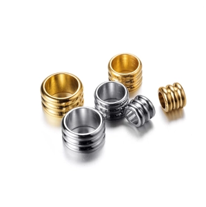 Gros plan de perles d'espacement cylindriques nervurées en acier inoxydable or et argent