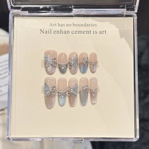 Blue cat-eye press-on nails set with silver bows, pearls, and sparkling rhinestones