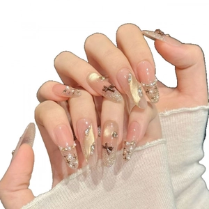 Cat eye press-on nails with brown bows, gold glitter, and pearl accents on white knit background