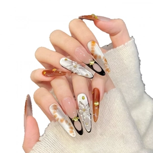 Handmade stiletto press-on nails with 3D white floral carvings and amber smudge effect