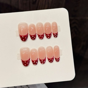 French tip press-on nails with red polka dots on long round translucent base