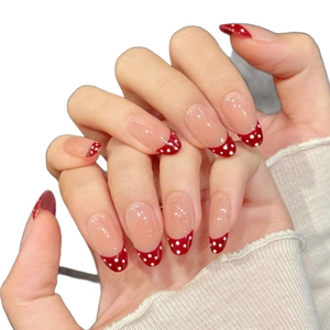 French press-on nails with red tips and white polka dots in an elegant long oval shape