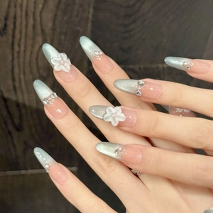 Handmade almond press-on nails with blue cat-eye gradient and 3D white floral crystals
