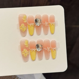 Handmade press-on nails with yellow floral decor and rhinestones in almond shape