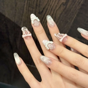 Pink and white gradient press-on nails with 3D bows, pearls and cat eye shimmer