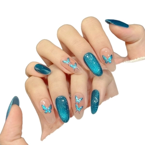 Blue cat-eye glitter press-on nails with butterfly designs and long almond shape