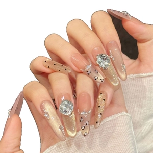 Sparkly cat-eye press-on nails with champagne gold glitter, black polka dots and rhinestones