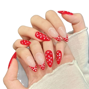 Faux ongles faits main à pois rouges et blancs avec une forme d'amande longue