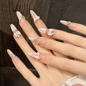 Pink gradient almond press-on nails with 3D bows and pearls on a model hand