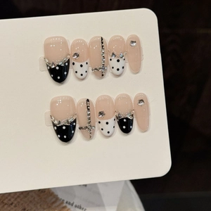 Unghie finte artigianali con pois bianchi e neri e dettagli a croce con strass brillanti