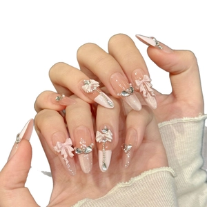 Handmade almond press-on nails with orange-pink gradient, 3D bows, and heart charms