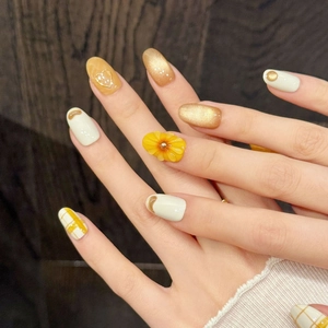 Handmade press-on nails featuring orange floral patterns and gold cat-eye finish