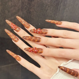 Long stiletto press-on nails with amber texture and 3D red floral art accents
