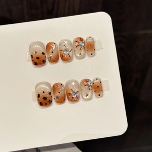 Press-on nails with leopard print, stars and rhinestones in orange gradient cat-eye style