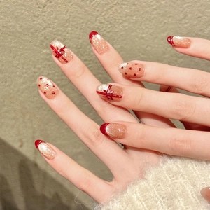 Faux ongles faits main rouge et or avec nœuds 3D et bordure French style pailletée
