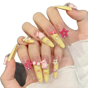 Pink and yellow stiletto press-on nails with 3D pigs, bows, and sparkling rhinestones