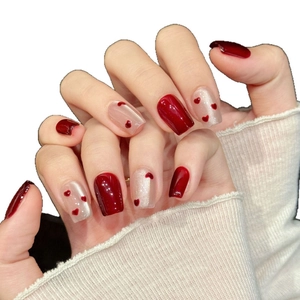 Handmade press-on nails with deep red finish and white heart patterns on square tips