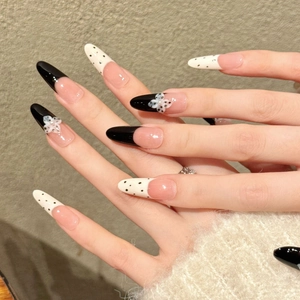 Elegant long almond press-on nails with black and white polka dots and 3D floral accents