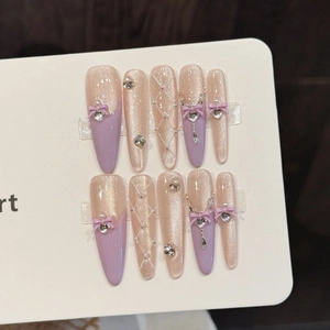 Faux ongles faits main œil de chat rose avec nœuds 3D violets et strass brillants