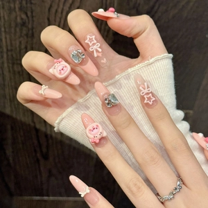 Pink gradient handmade press-on nails with 3D cartoon bear and bow charms on model hands