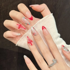 Faux ongles de Noël avec nœuds rouges dessinés à la main et dégradé de paillettes argent