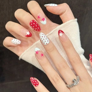 Sweet red and white polka dot press-on nails with star patterns shown on hand