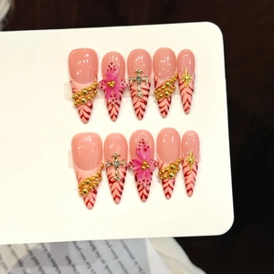 Pink and red marbled press-on nails with 3D gold cross and floral accents in almond shape