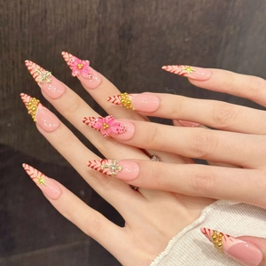 Pink press-on nails with red stripes, floral charms and golden cross accents