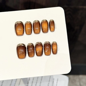 Faux ongles faits main œil de chat marron avec bords métalliques et strass brillants