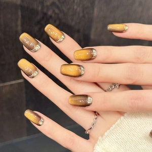 Faux ongles dégradé caramel avec effet œil de chat doré et bordure métallique