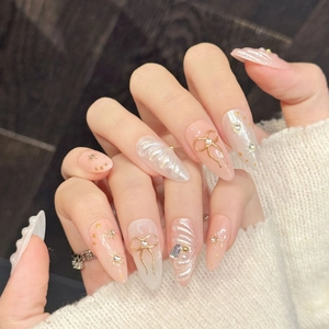 Handmade pink almond press-on nails with gold 3D bows and shimmering pearl shell details
