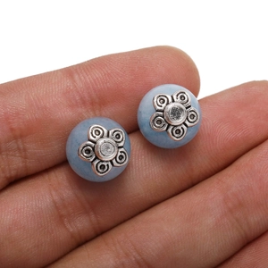 Retro light blue mineral earrings with silver flower caps held to show product scale