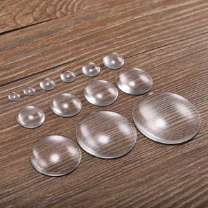 Macro shot of transparent round glass cabochons in various sizes on a wood surface
