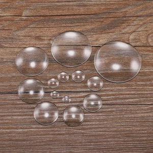 Macro view of transparent round glass cabochons in various sizes on a wood surface
