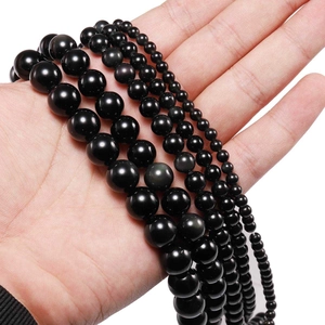 Natural black obsidian loose round beads in four different sizes shown on hand for comparison