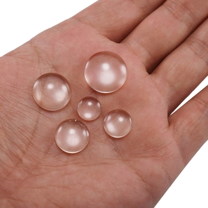 Clear round glass cabochons for DIY jewelry making shown on hand for scale