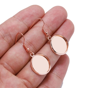 Close-up of rose gold oval earring base hooks held by hand for DIY jewelry making