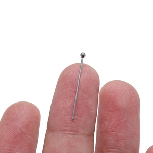 Silver stainless steel ball head pins for jewelry making shown with hand for scale