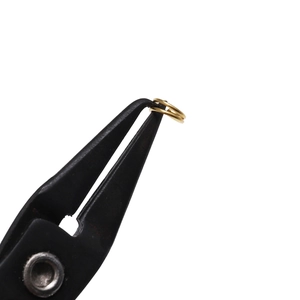 Macro shot of gold jump rings being held with professional jewelry pliers for DIY craft