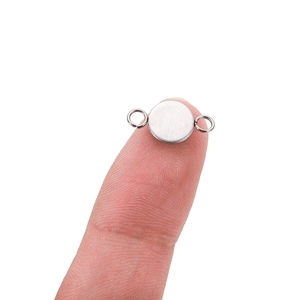 DIY runder Edelstahl-Verbinder mit Ösen, gezeigt am Finger zum Größenvergleich