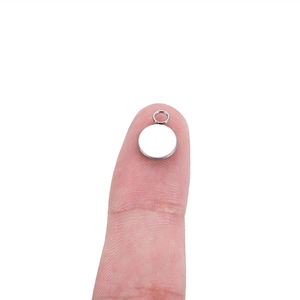Polished stainless steel round pendant tray for DIY jewelry on a person finger tip